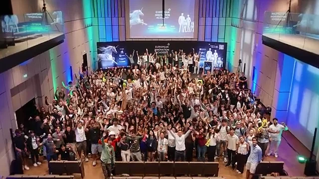 The EIA 2026 cohort in the main hall in Porto, arms raised